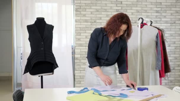 Tailor nő intézkedések ruhával használja szalagot az asztalra, hogy a minta a jövő ruhákat. - Felvétel, videó