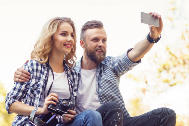 Young loving couple making selfie photo in autumn park. - 写真・画像