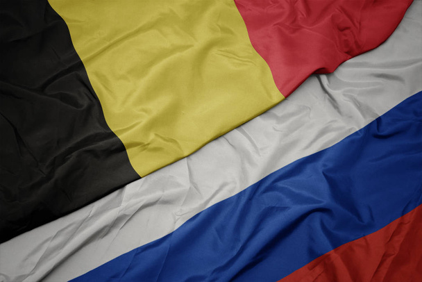 размахивая красочным флагом России и национальным флагом Бельгии
. - Фото, изображение