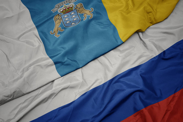 schwenken bunte Flagge Russlands und Nationalflagge der Kanarischen Inseln. - Foto, Bild