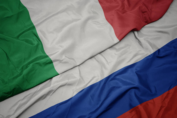 ondeando colorida bandera de Rusia y bandera nacional de Italia
. - Foto, imagen