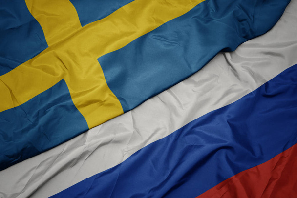 κυματιστό πολύχρωμο σημαία της Ρωσίας και της εθνικής σημαίας της Σουηδίας. - Φωτογραφία, εικόνα