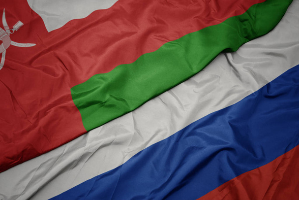 Orosz zászló színpompás zászlója és Omán nemzeti zászlaja. - Fotó, kép