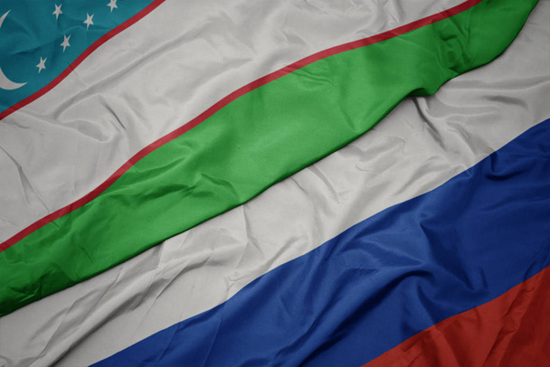 ondeando colorida bandera de Rusia y bandera nacional de Uzbekistán
. - Foto, imagen