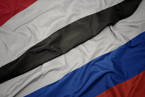 розмахуючи барвистим прапором Росії та національним прапором Ємену. - Фото, зображення