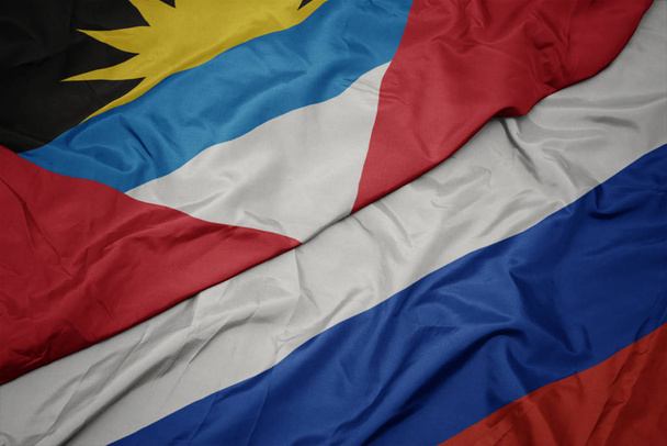 waving colorful flag of russia and national flag of antigua and barbuda. - Photo, Image