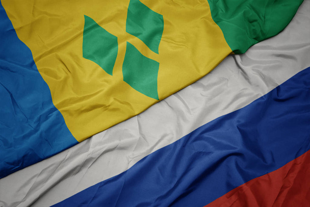schwenken bunte Flagge Russlands und Nationalflagge des Heiligen Vincent und der Granadinen. - Foto, Bild