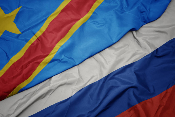 schwenkt die bunte Flagge Russlands und die Nationalflagge der Demokratischen Republik Kongo. - Foto, Bild