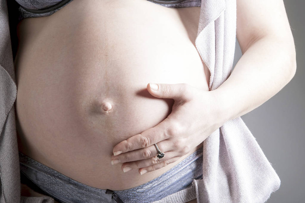 Belly of a pregnant woman with a hand on it close up. - Photo, Image