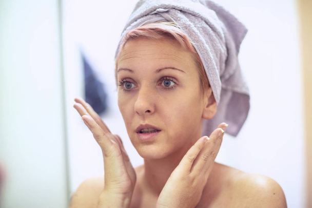 Girl is worried about the wrinkles on her face. Skin care concep - Photo, Image