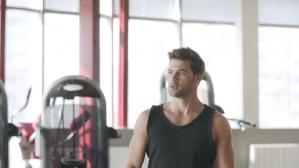 Handsome man doing lunges exercise with dumbbells in fitness club. - Footage, Video