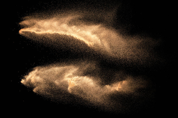 Bruin gekleurd zand spetteren tegen donkere achtergrond. Droge rivierzand explosie geïsoleerd op zwarte achtergrond. Abstract zand wolk. - Foto, afbeelding