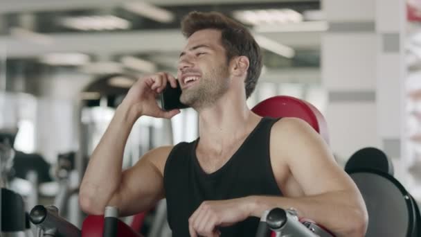Handsome man talking mobile in fitness club. Closeup sportsman having break - Záběry, video