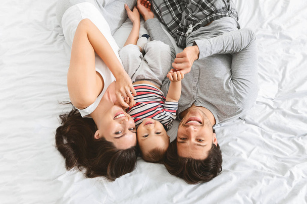 Positiivinen perhe halailu sängyssä vauvan pojan kanssa
 - Valokuva, kuva