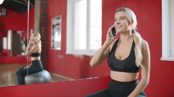 Mujer sonriente hablando de teléfono móvil en un club saludable. Mujer feliz usando smartphone
 - Metraje, vídeo