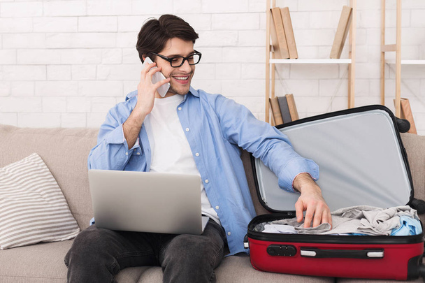 Young man preparing for trip and talking on phone - Photo, image