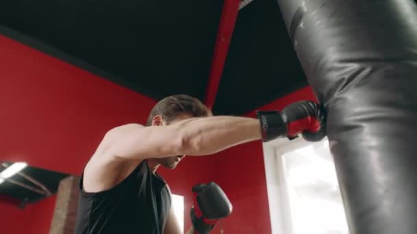 Боксерський чоловік штовхає бойовий мішок у спортзалі з низьким кутом зору
. - Кадри, відео