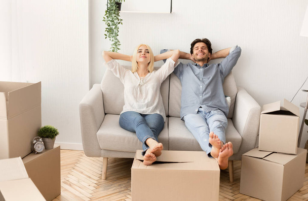 Radostný manžel a manželka relaxační na gauči v novém domě - Fotografie, Obrázek