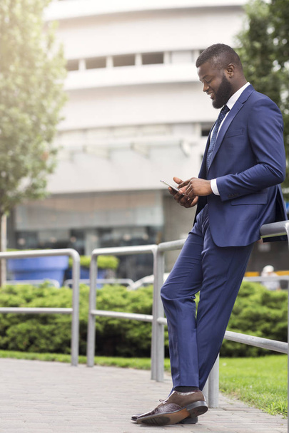Africká americká obchodní osoba používající mobilní telefon venku - Fotografie, Obrázek