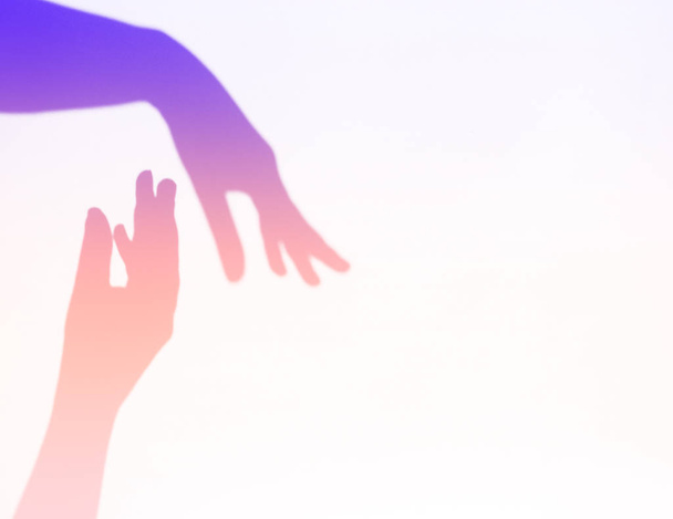 Neon getint. twee vrouwenhanden reiken voor elkaar. Helpende hand silhouet, vrouwelijke en mannelijke samen - Foto, afbeelding