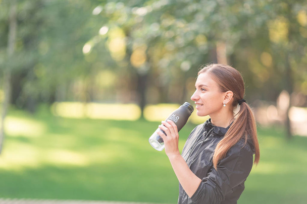 Happy sportive woman drinking water during fitness exercises - Foto, imagen