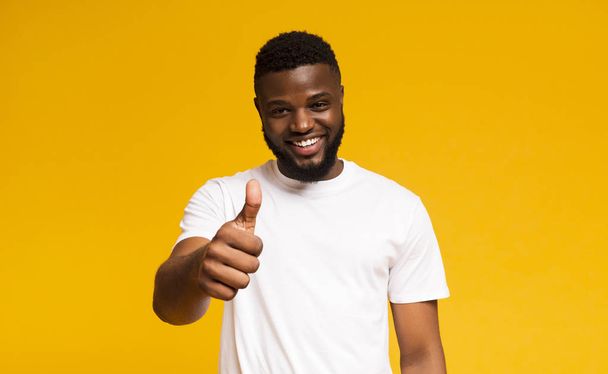 Happy guy showing thumb up and smiling over yellow background - Photo, Image