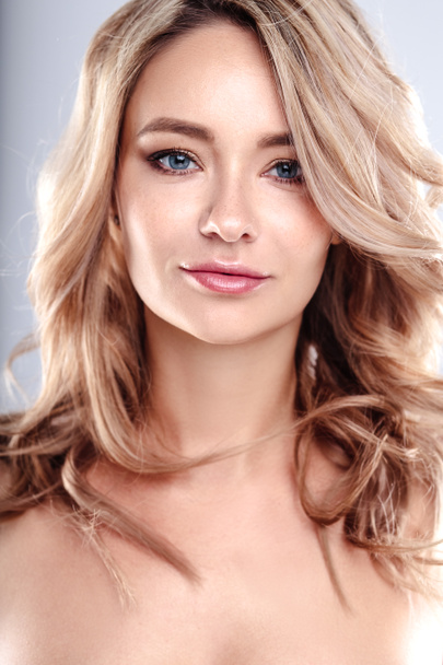 Blonde young woman with healthy curly hair and natural make up . Beautiful model girl with wavy hairstyle. Care and beauty - Foto, Bild
