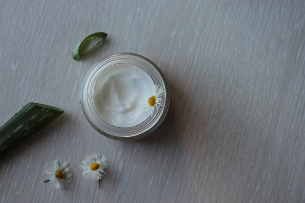 Üvegedénybe fehér kozmetikai krém, Aloe és a Kamilla egy bézs háttér. - Fotó, kép
