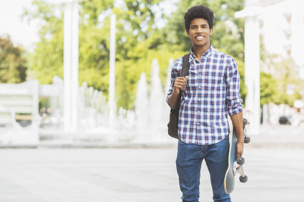 Handsome male teenager with skateboard posing to camera - Zdjęcie, obraz