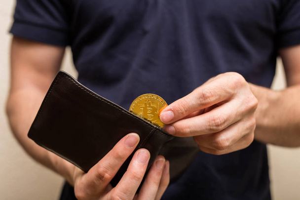 Чоловік бере золотий біткоїн зі свого гаманця, віртуальної валюти. Криптовалюта. Нові віртуальні гроші. бізнесмен Відкритий гаманець
. - Фото, зображення