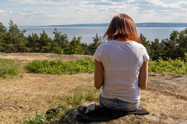 A girl sits on a mountain on the background of the sea - Zdjęcie, obraz