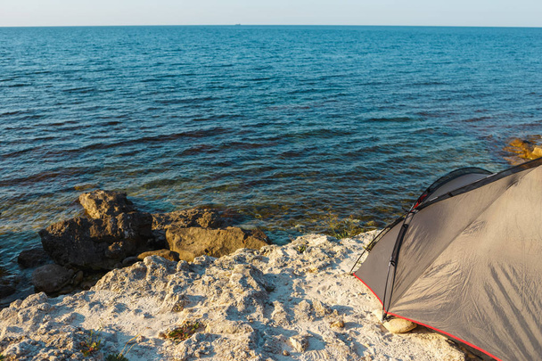 The tent stands on a rocky seashore - Φωτογραφία, εικόνα