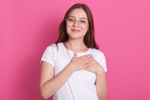 Young beautiful caucasian female wearing white casual t shirrt, stands smiling with hands on chest and grateful gesture on face, having pleasant facial expession, isolated on pink wall. Health concept - Foto, afbeelding