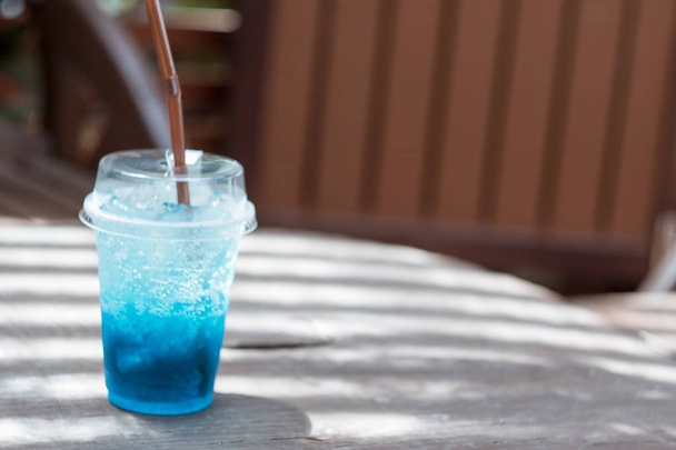 Blaue Limonade in einem Plastikglas auf einem Holztisch - Foto, Bild