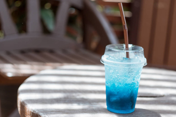 Blaue Limonade in einem Plastikglas auf einem Holztisch - Foto, Bild