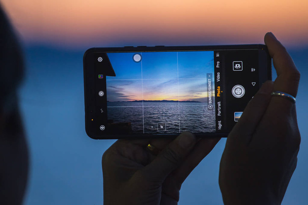 The picture of the beautiful sunset in the sea on the phone - Photo, Image