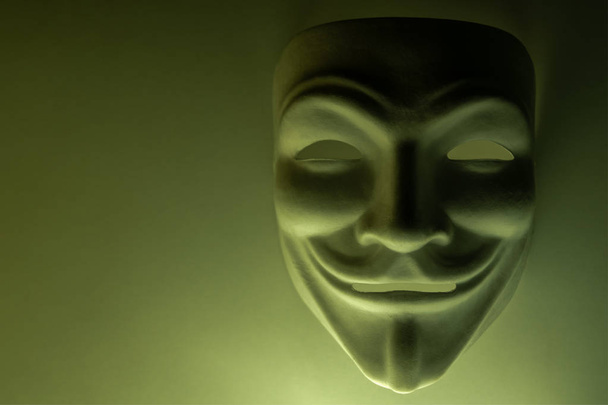 Una maschera che sembra un simbolo di un gruppo di hacker anonimi. Colorato in colore oliva. Sparare a un soggetto in chiave oscura. Sfondo per screensaver o desktop wallpaper monitor. Primo piano. Copia spazio
. - Foto, immagini