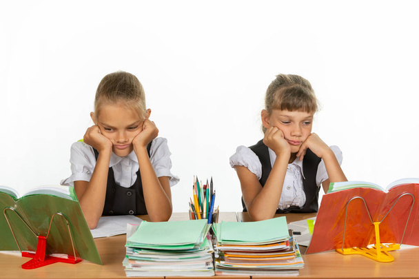 Traurige Schulmädchen schauen sich im Unterricht Lehrbücher an - Foto, Bild