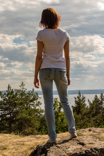Girl stands on a rock against the sea - Foto, afbeelding