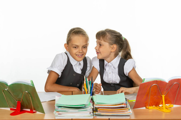 Deux filles chuchotent alors qu'elles sont assises à un bureau
 - Photo, image