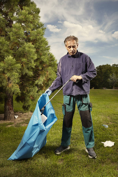 Man in public service cleaning up trash in city park - Foto, Bild