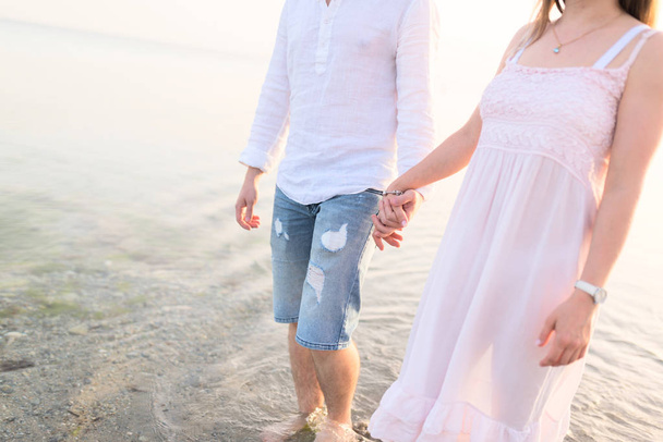 Couple holding hands walking romantic on beach on vacation travel holidays. Closeup of body and golden sand for copy space. Young loving couple  - Foto, imagen