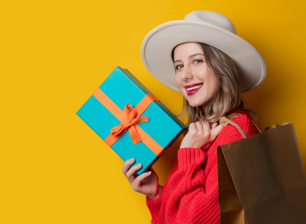 smiling woman in red sweater with gift box and shopping bag - Photo, Image
