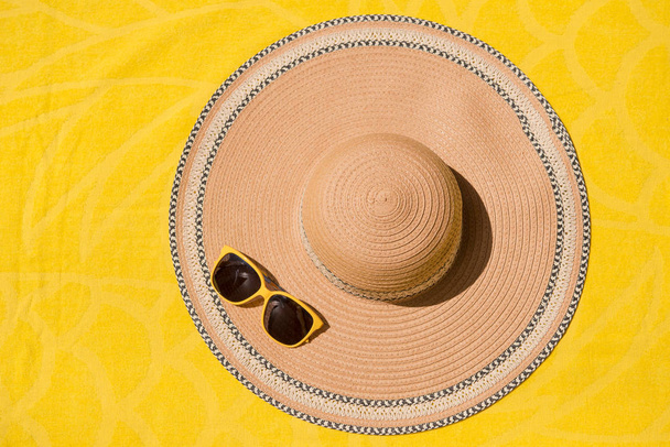 Hat and sunglasses. On yellow background. Summer holiday and travel concept. Copy space background, top view flat lay overhead. - Photo, Image