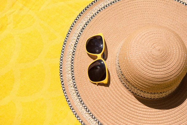 帽子とサングラス黄色の背景に。夏休みと旅行のコンセプト。コピースペースの背景、上のビューフラットレイオーバーヘッド. - 写真・画像