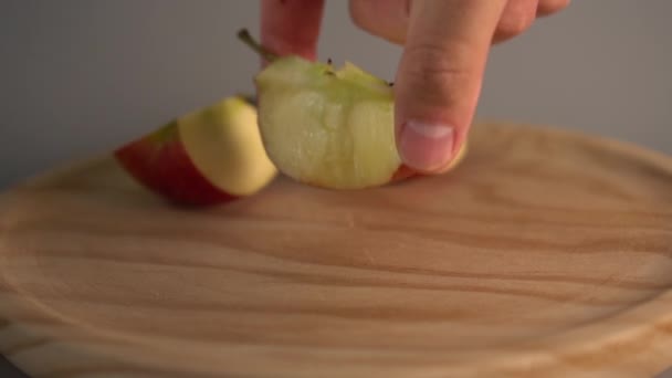 Hand lays a bitten half of a ripe red apple on a wooden surface. Slow motion - Filmagem, Vídeo