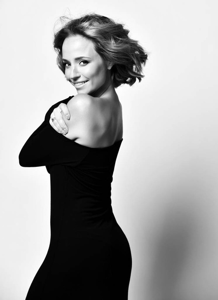 Belle actrice aux cheveux bouclés heureux émotions du visage en robe noire posant en souriant. Noir et blanc
  - Photo, image
