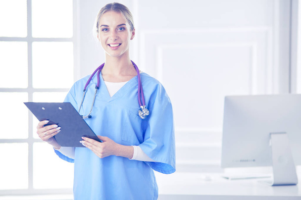 Smiling female doctor with a folder in uniform standing - Zdjęcie, obraz