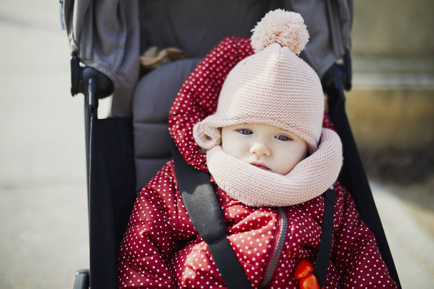 girl in bright stylish clothes sitting in pushchair outdoors on a fall day - Fotografie, Obrázek