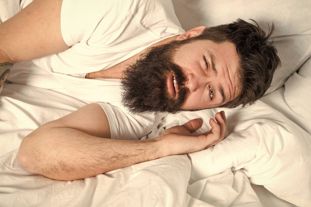 Lazy morning. Relax and sleep concept. Man bearded guy sleep on white sheets. Healthy sleep and wellbeing. Man bearded hipster sleepy in bed. Early morning hours. Insomnia and sleep problems - Foto, imagen